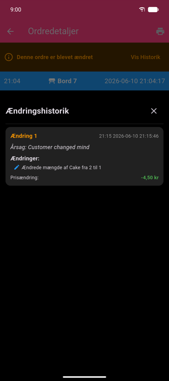 Skærm med ordredetaljer med et orange 'Denne ordre er blevet ændret'-banner og Vis Historik-link; blå overskrift der viser 21:04, Bord 7, 2026-06-10 21:04:17; Ændringshistorik-bundark der viser Ændring 1 med årsagen 'Kunden skiftede mening', ændring 'Ændrede antal af Kage fra 2 til 1' og Prisændring: −4,50 kr i grønt